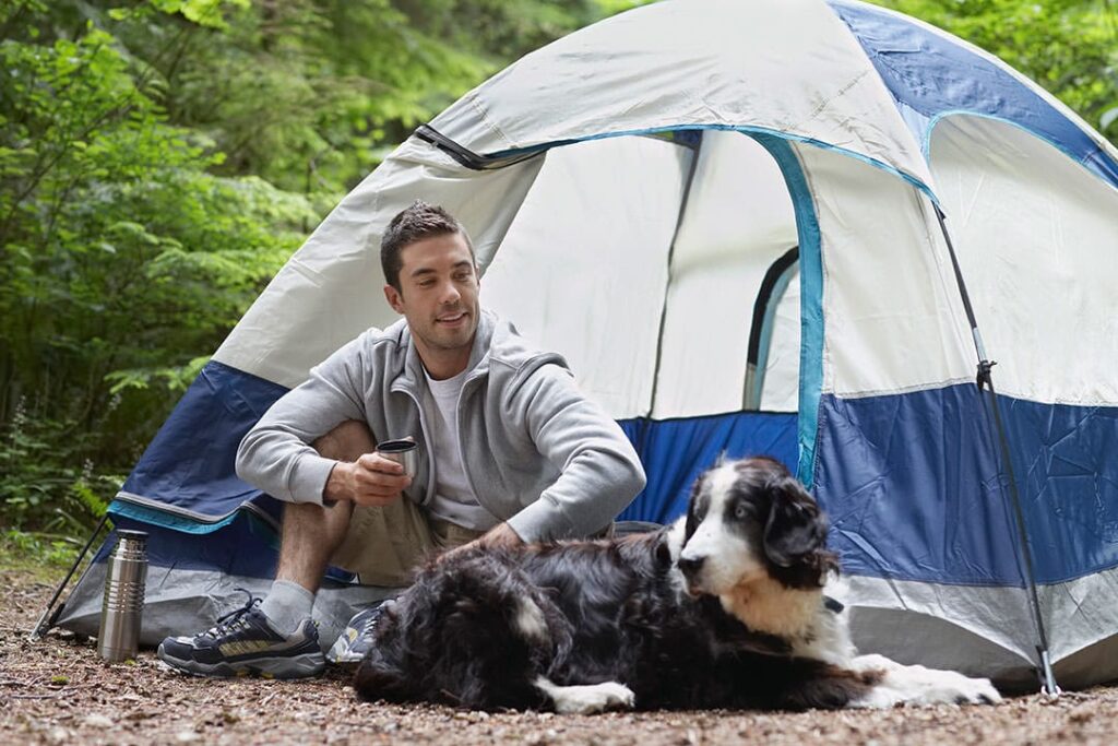 guy camping with dog at tent